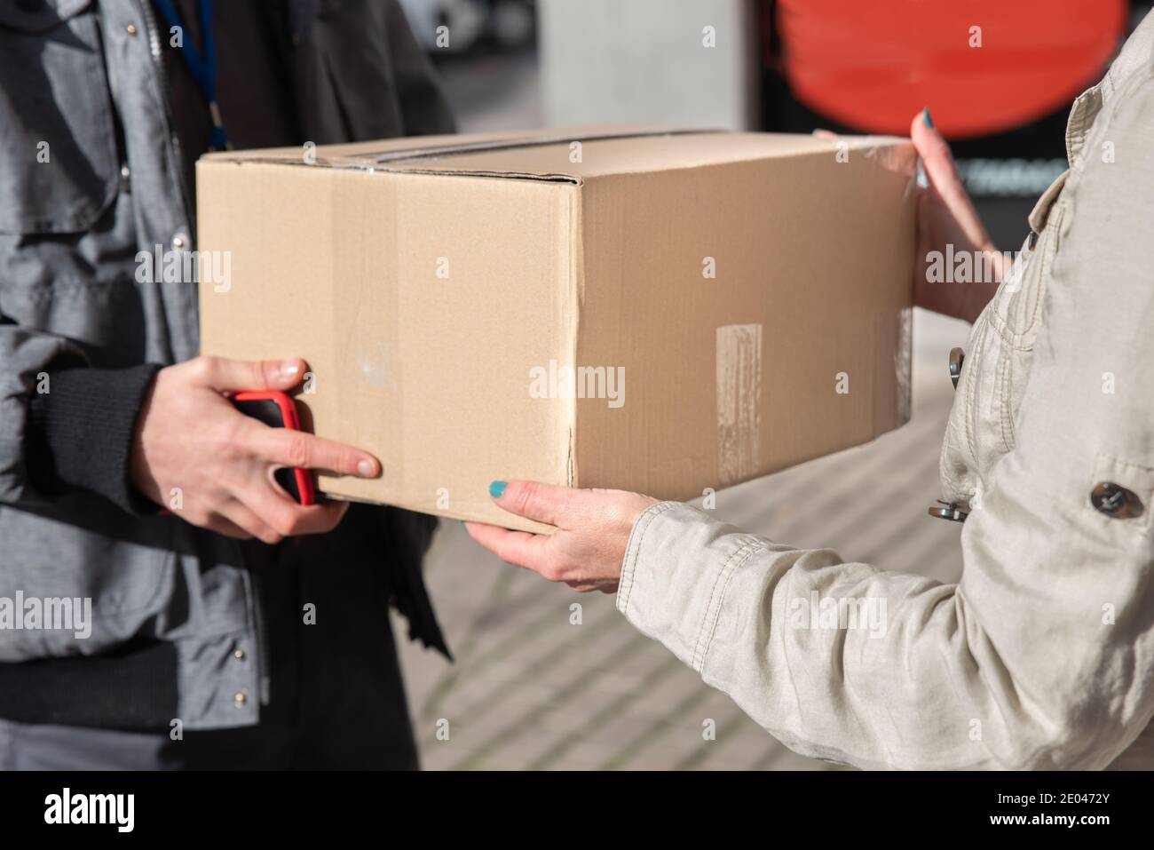 Uomo di consegna con il telefono cellulare in mano mani su un box alla donna Foto Stock