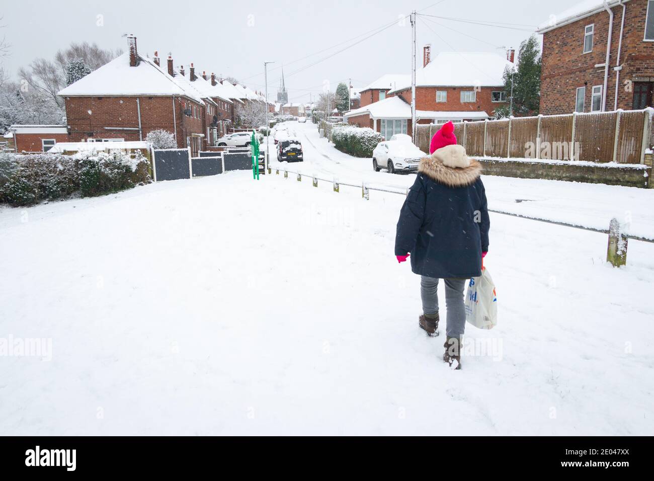 donna vestita per il tempo in una scena suburbana nevosa Foto Stock