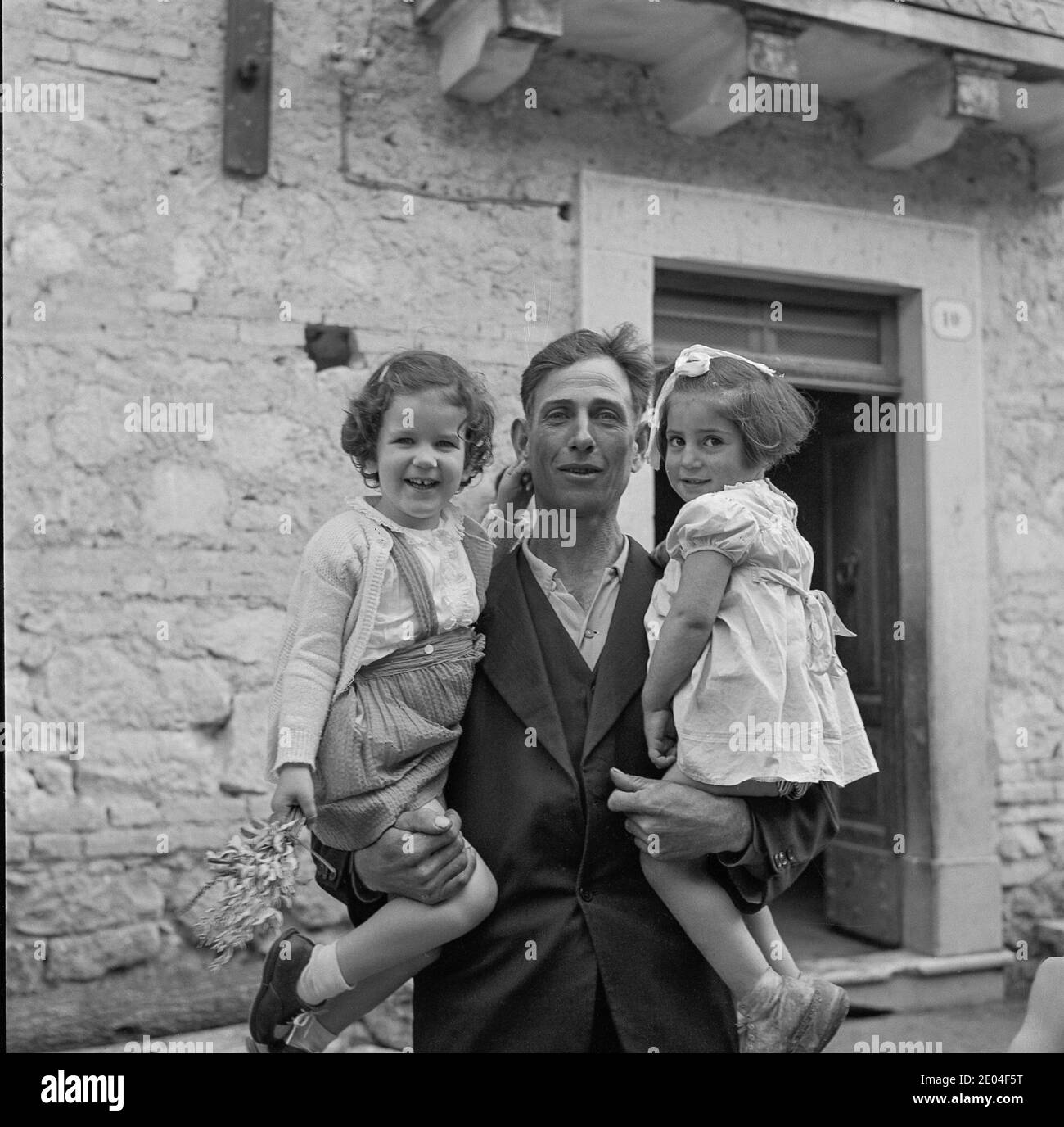 Local Man Holding Two Girls, 1951, LAquila, Italia Foto Stock