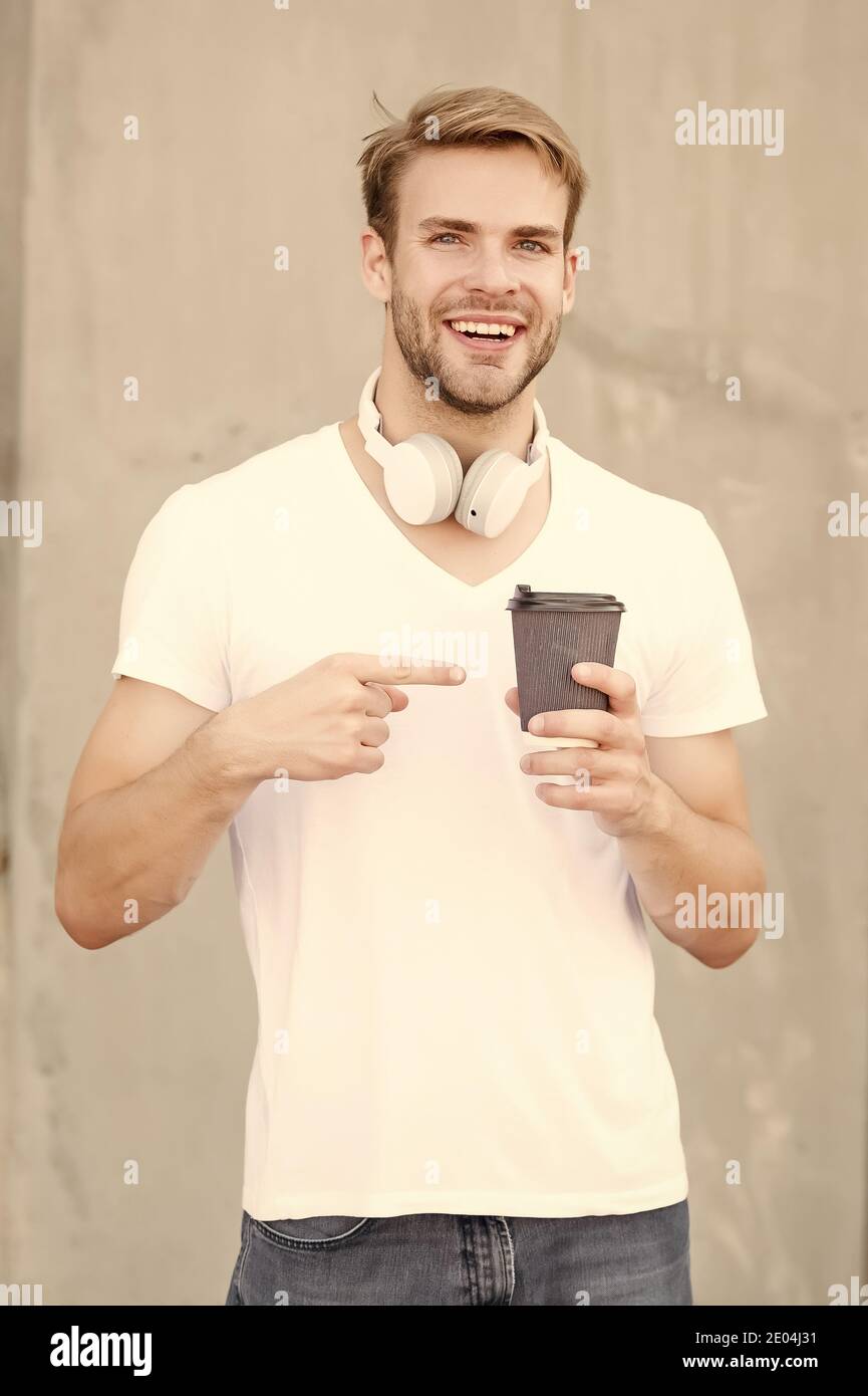 Provare. Uomo felice che punta alla tazza calda all'aperto. Gesto di riferimento per bere da asporto. Punta del dito indice. Puntando per la pubblicità. Ordinate caffè, tè o cioccolata calda. Bevanda da portare via. Foto Stock