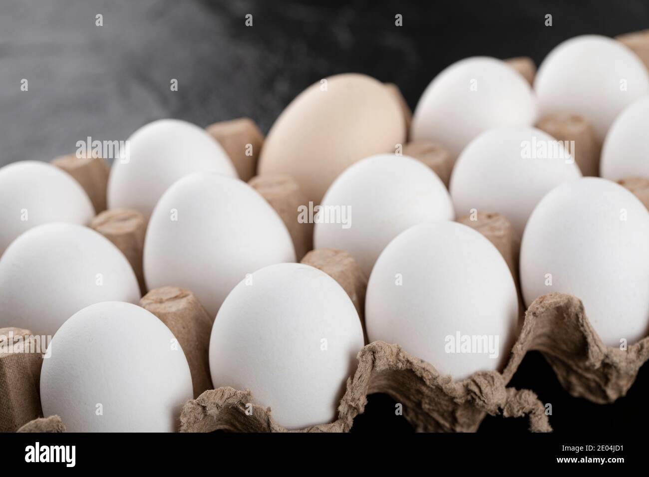 Contenitore di uova bianche su fondo nero Foto Stock