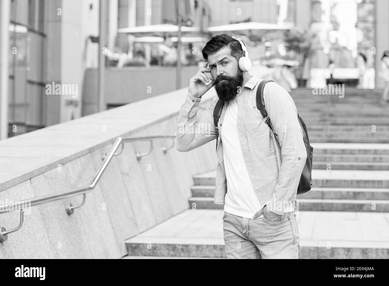 Percorso giornaliero al lavoro. Vita moderna. Uomo con cuffie che cammina nel centro della città. Ascoltare musica. Modifica del concetto di scenario. Bello hipster con zaino strada a piedi. Camminando per strade vuote. Foto Stock