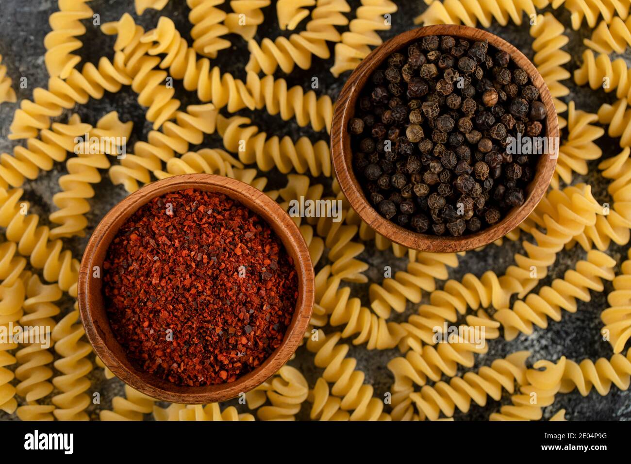 Pasta di fusilli crudi e spezie al pepe su sfondo marmoreo Foto Stock