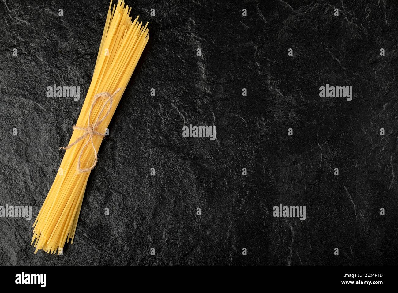 Spaghetti crudi legati con corda su fondo nero Foto Stock