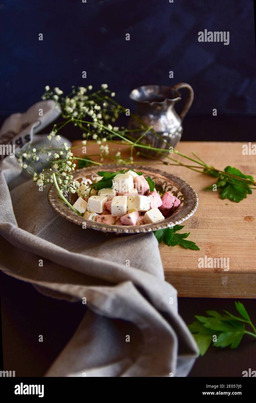 Una ciotola di formaggio feta con erbe su un tavolo di legno su sfondo nero. Foto Stock