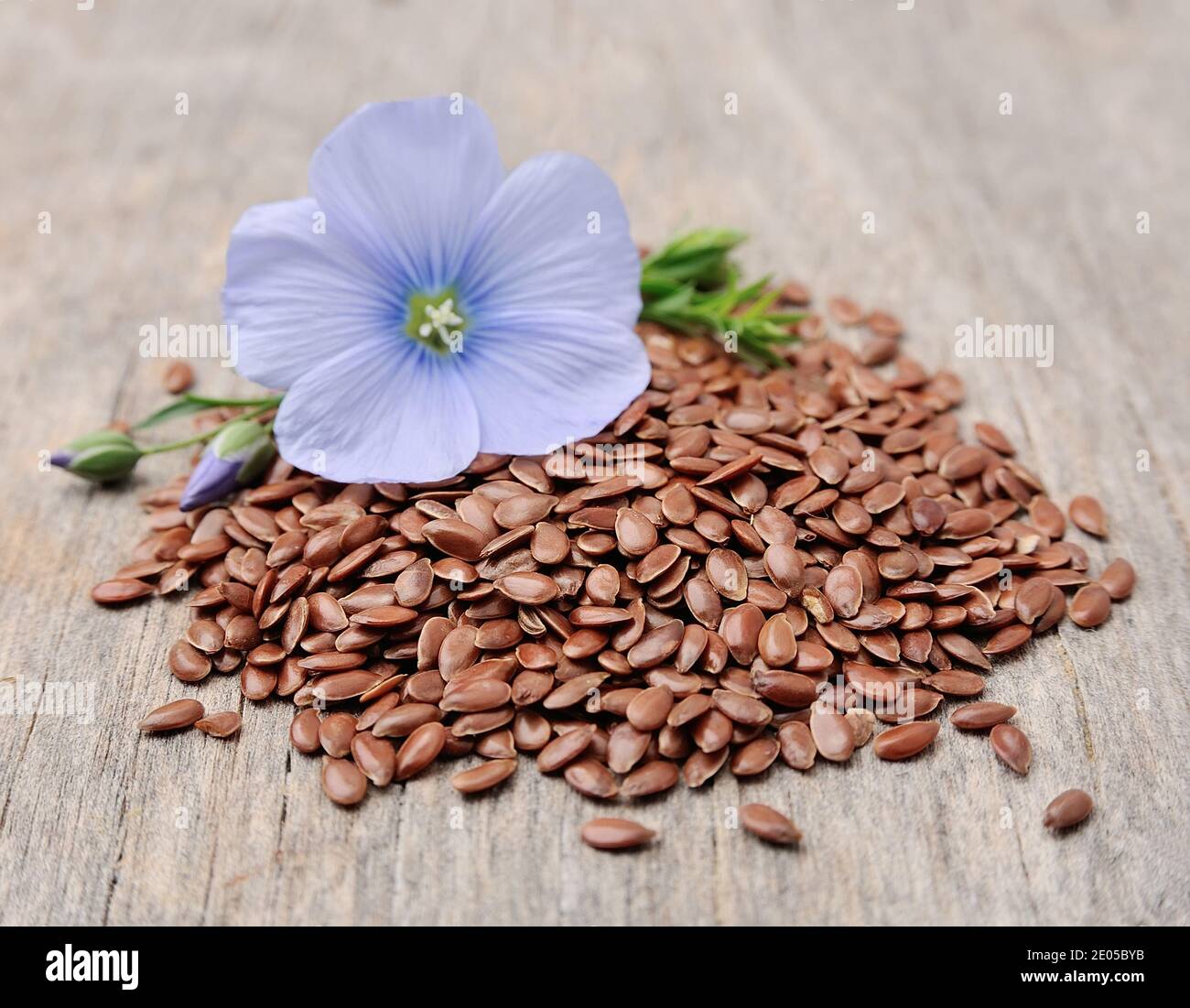 Semi di lino con fiori da vicino su tessitura di legno Foto Stock