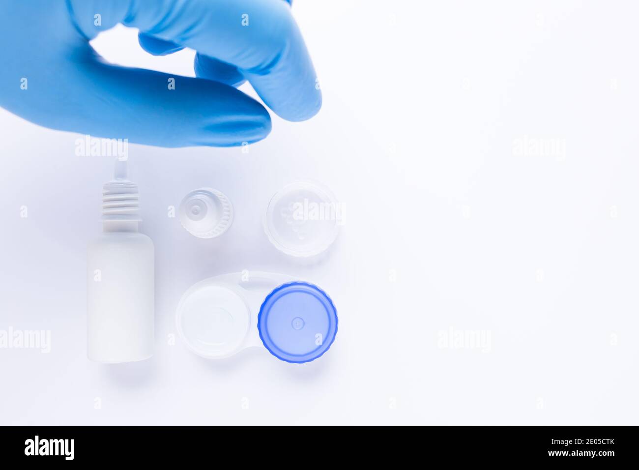 la mano con il guanto blu sta per prendere un portaobiettivo a contatto su sfondo bianco, con spazio per la copia. Foto Stock
