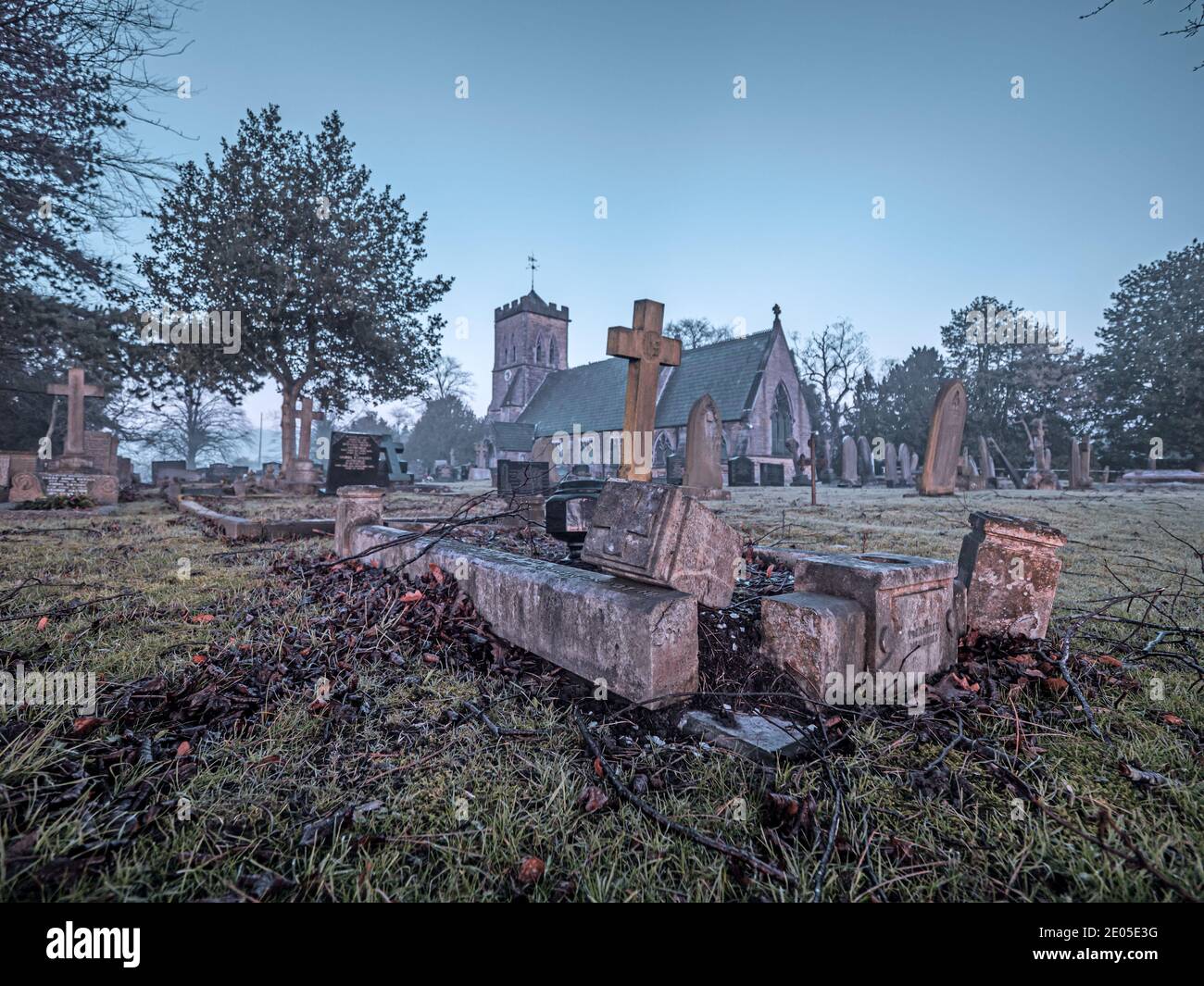 Un'immagine solenne di lapidi in un cortile della chiesa su una nebbiosa Moody alba. Foto Stock