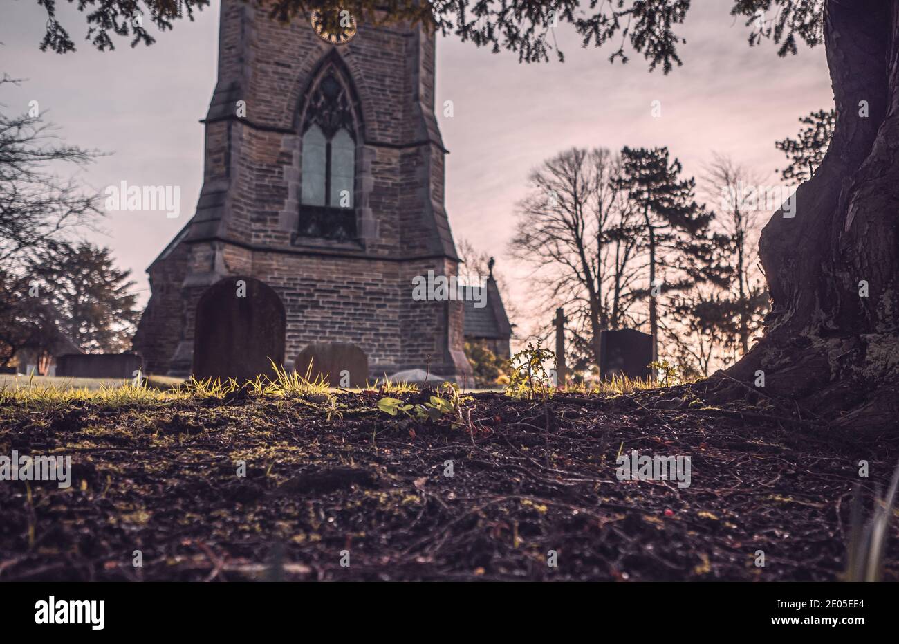Un'immagine solenne di lapidi in un cortile della chiesa su una nebbiosa Moody alba. Foto Stock