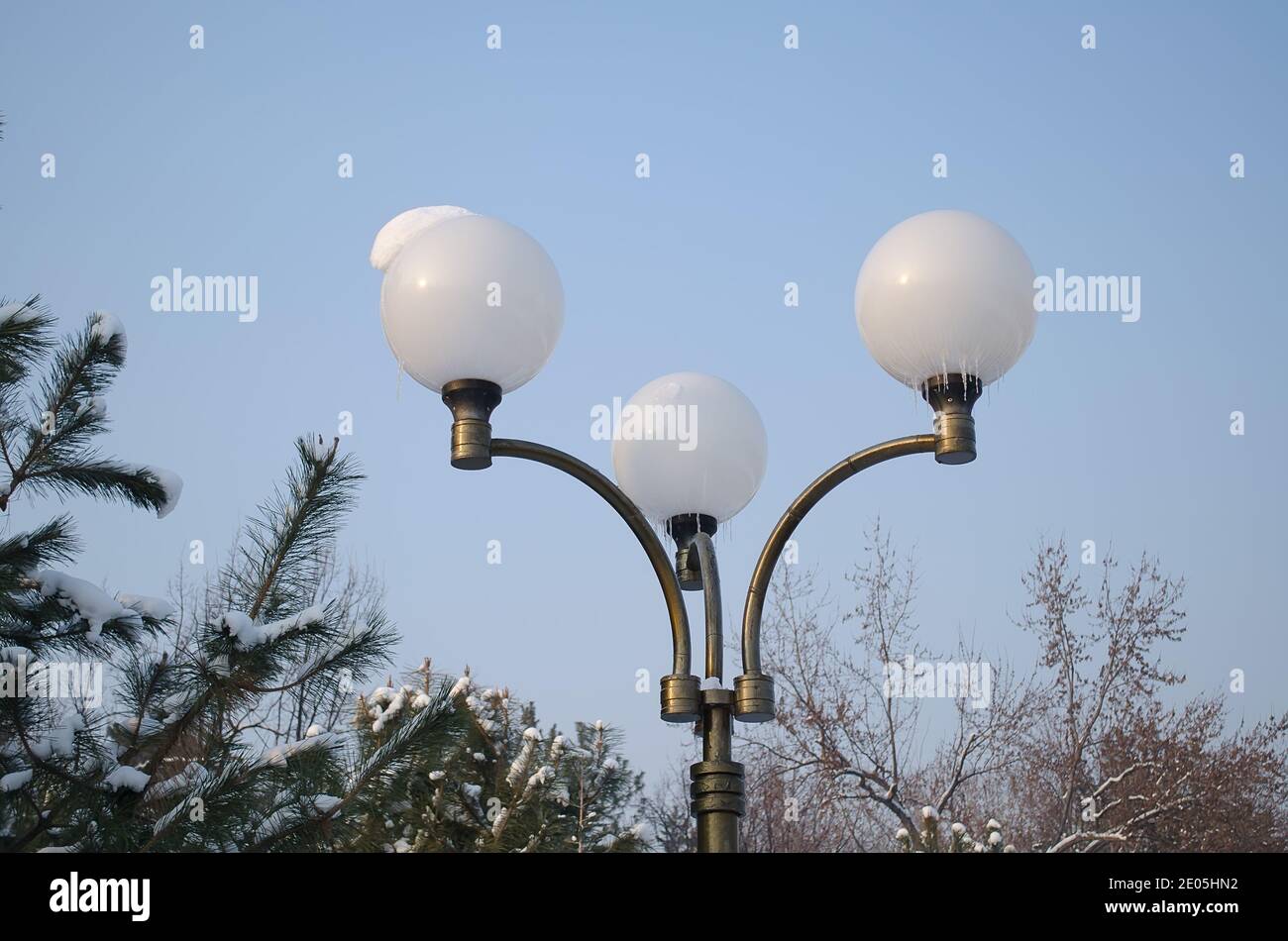 Lanterna di ferro con tre plafonds rotondi, ricoperta di neve e di ghiaccio in inverno, sullo sfondo del cielo e degli alberi di Natale Foto Stock