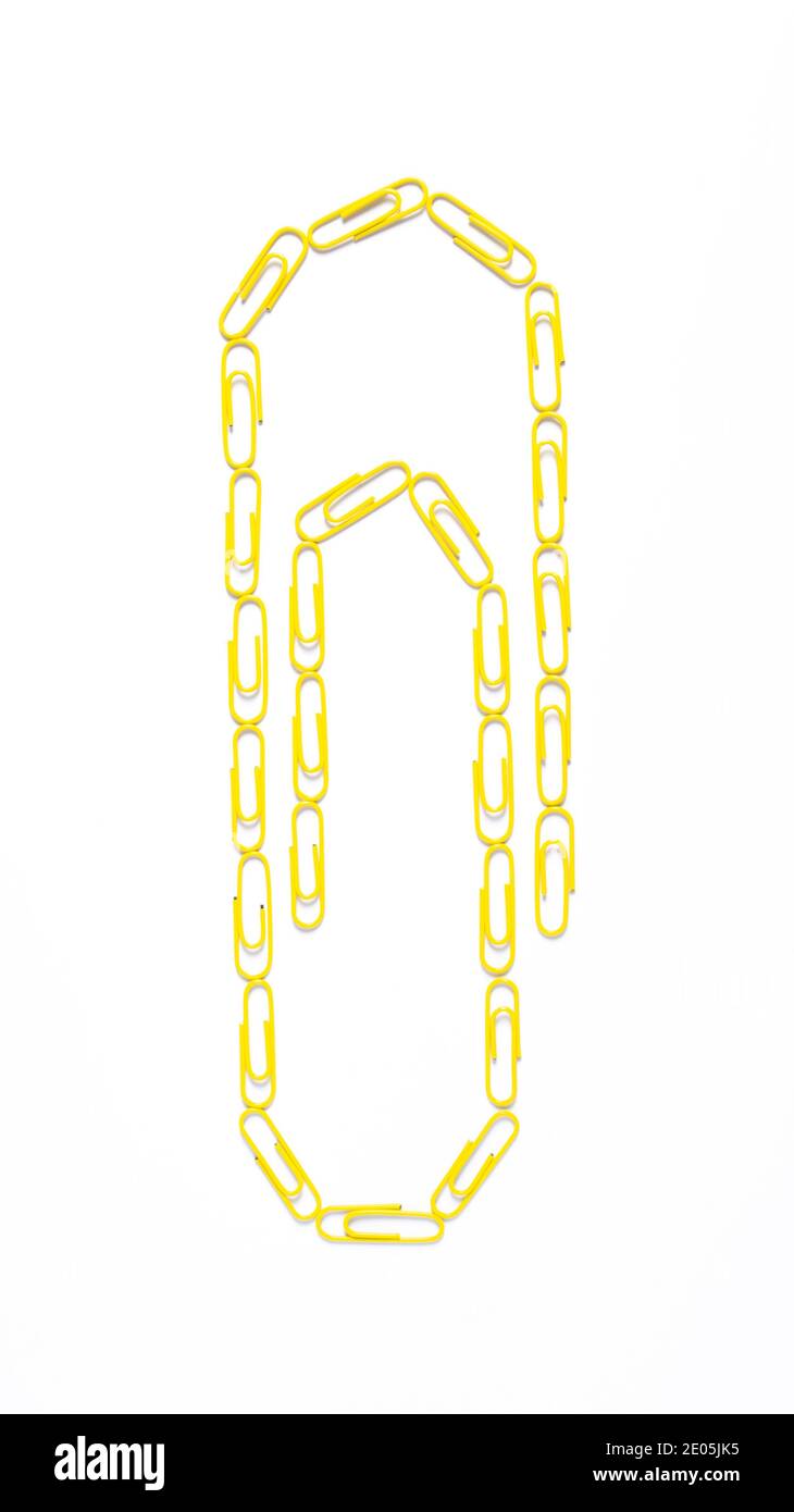 Forma di graffetta realizzata con fermagli di carta gialli su bianco Sfondo.Vista superiore Foto Stock