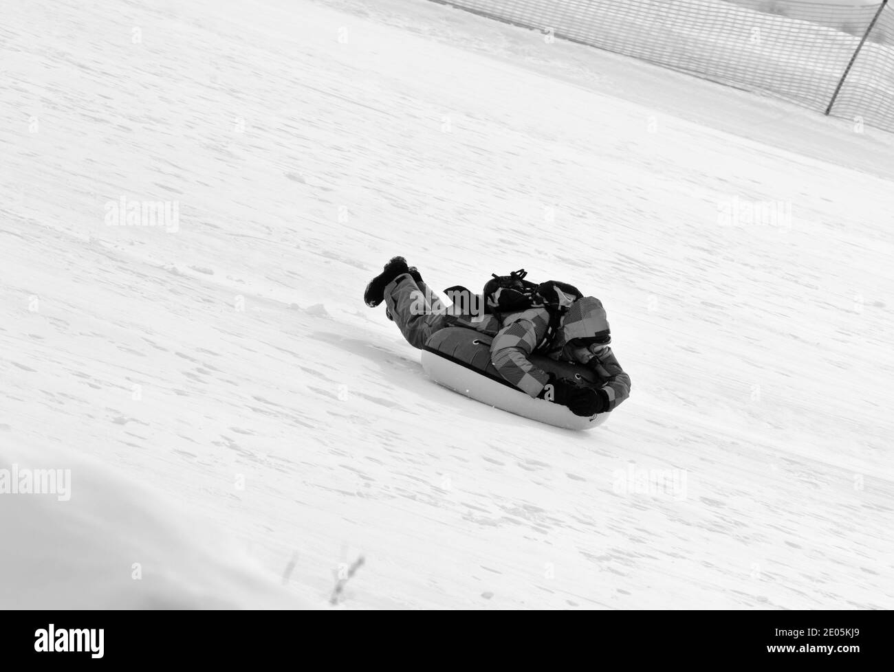 Tubing sulla stazione sciistica in giornata di sole in montagne innevate. Vacanza invernale. Immagine in bianco e nero. Foto Stock