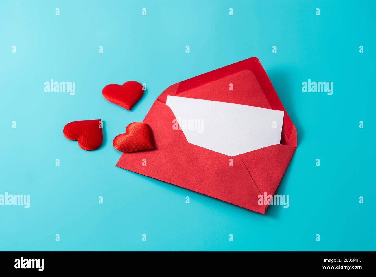 Cuori che escono da una busta rossa su sfondo blu Foto Stock