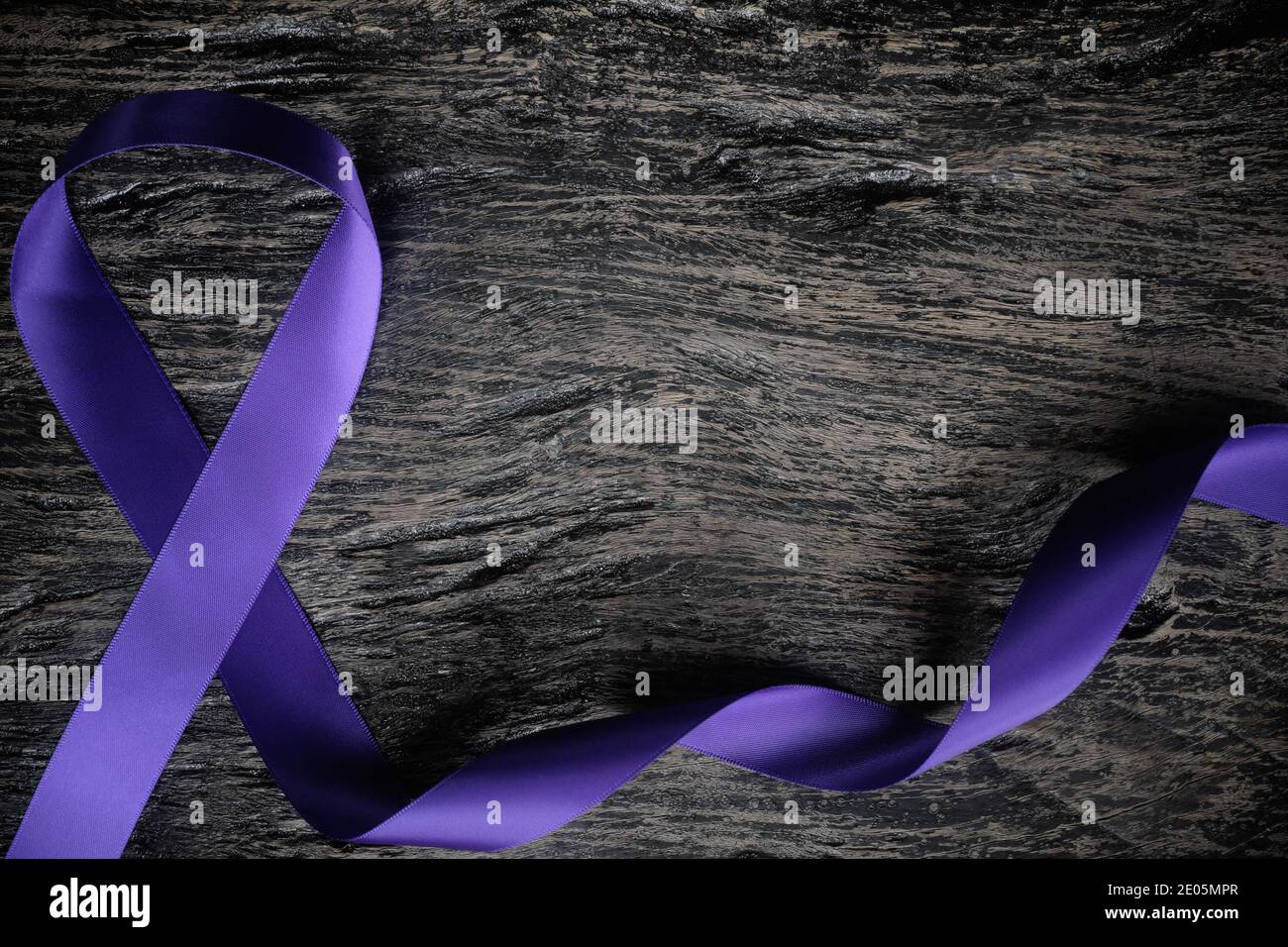 Vista dall'alto del nastro viola su sfondo di legno scuro con spazio per la copia. Concetto di consapevolezza del cancro del linfoma di Hodgkin. Foto Stock