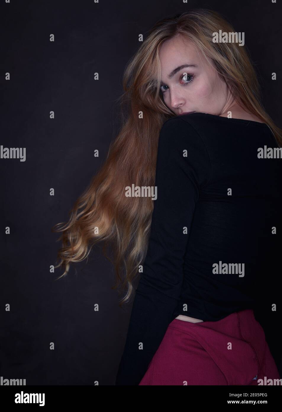 Immagine da studio di moda con un forte collegamento visivo che si affaccia sulla spalla con capelli lunghi che scorrono con una giovane donna naturalmente bella (20) Foto Stock