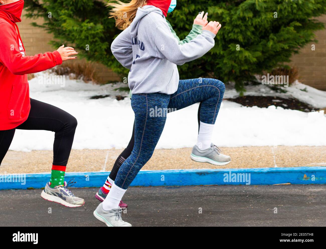 A causa della neve, una squadra di atletica delle scuole superiori si esibisce esecuzione di trapani nel parcheggio con maschere facciali a soffietto Durante 2020 coronavirus COVID-19 padella Foto Stock