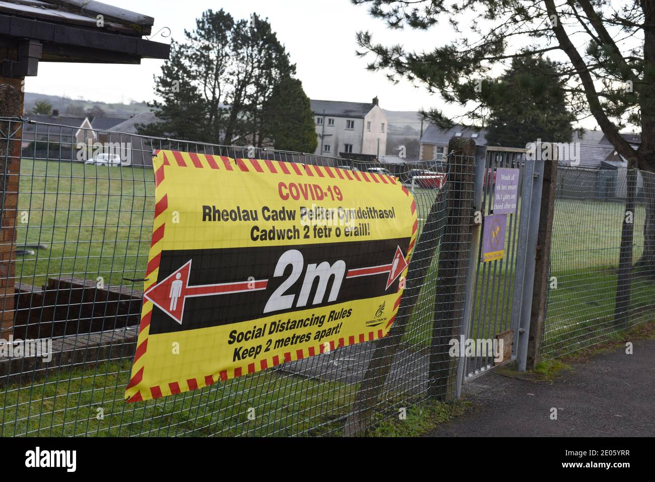 La segnaletica durante la pandemia di Covid-19 del 2020 variava in Galles a seconda che la scuola insegnasse nel mezzo del gallese o dell'inglese. Numero 3966 Foto Stock