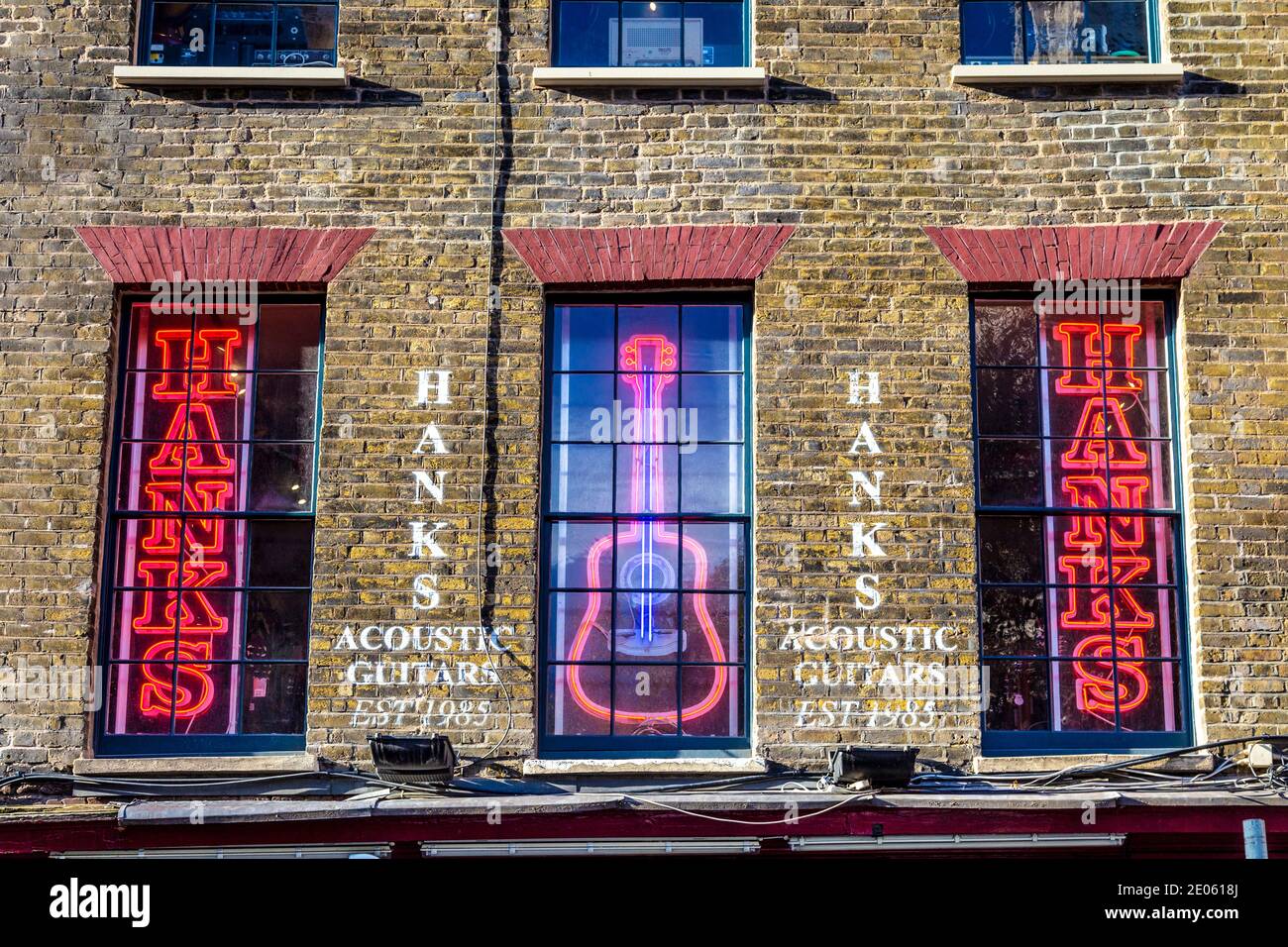 Insegne al neon nelle finestre del negozio di chitarra acustica Hanks sulla famosa strada del negozio di musica - Denmark Street, Londra, Regno Unito Foto Stock
