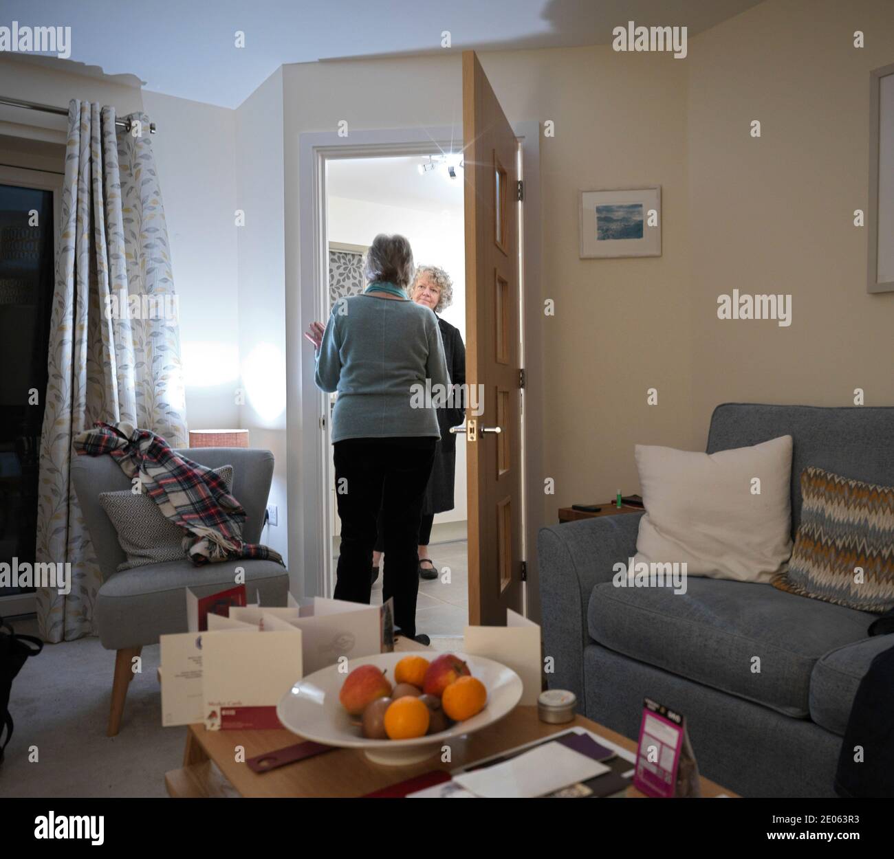 Un'anziana residente nel suo appartamento di pensionamento che viene ascoltata dalla figlia minore Foto Stock
