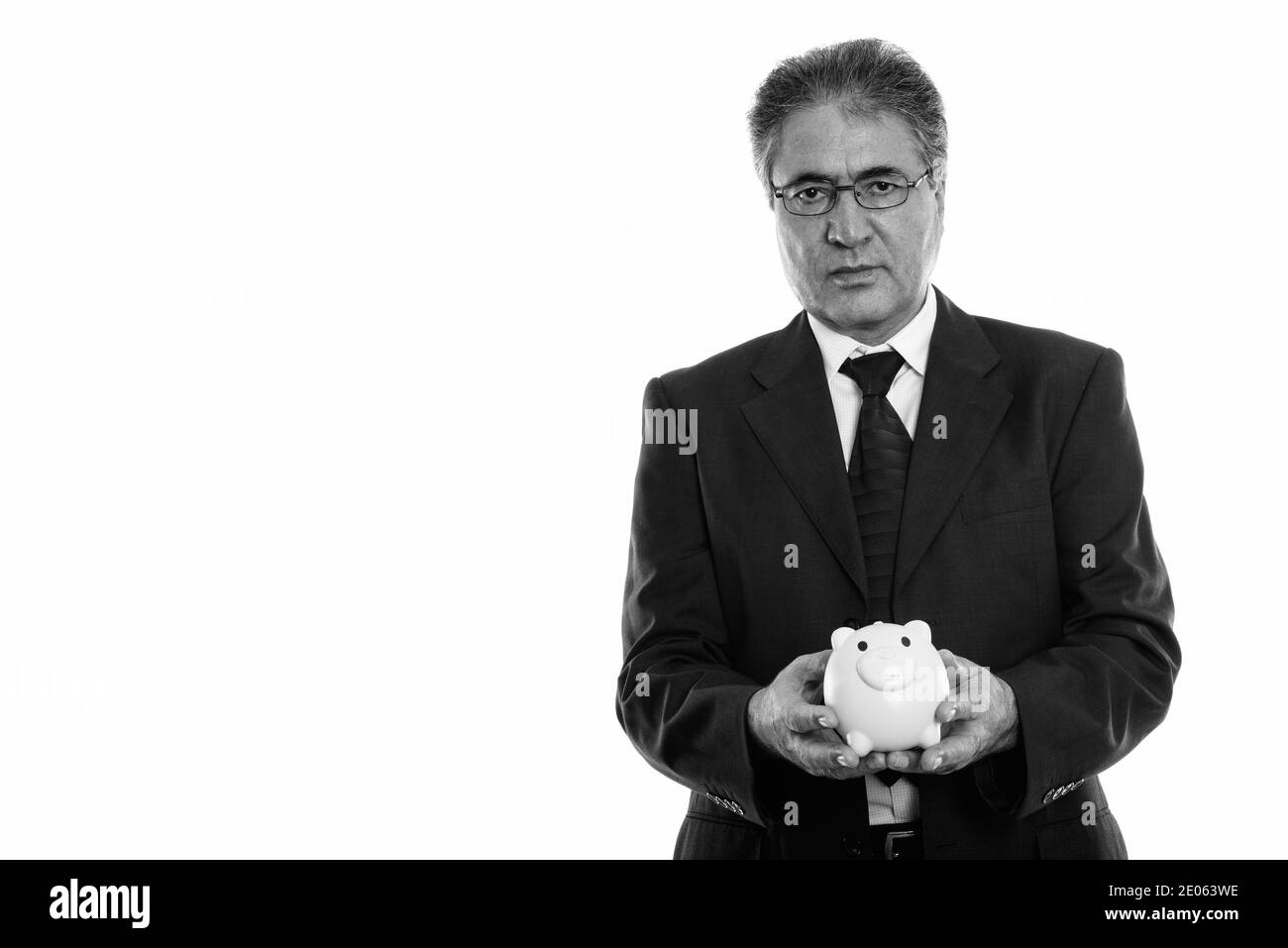Studio shot di senior imprenditore persiano holding salvadanaio Foto Stock