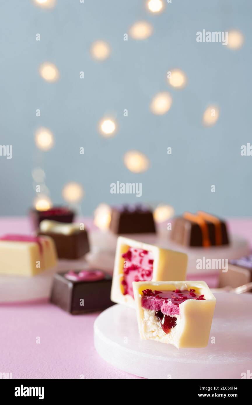 Bonbon caramelle al cioccolato decorato a mano e dessert di praline su rosa e sfondo blu con luci bokeh Foto Stock