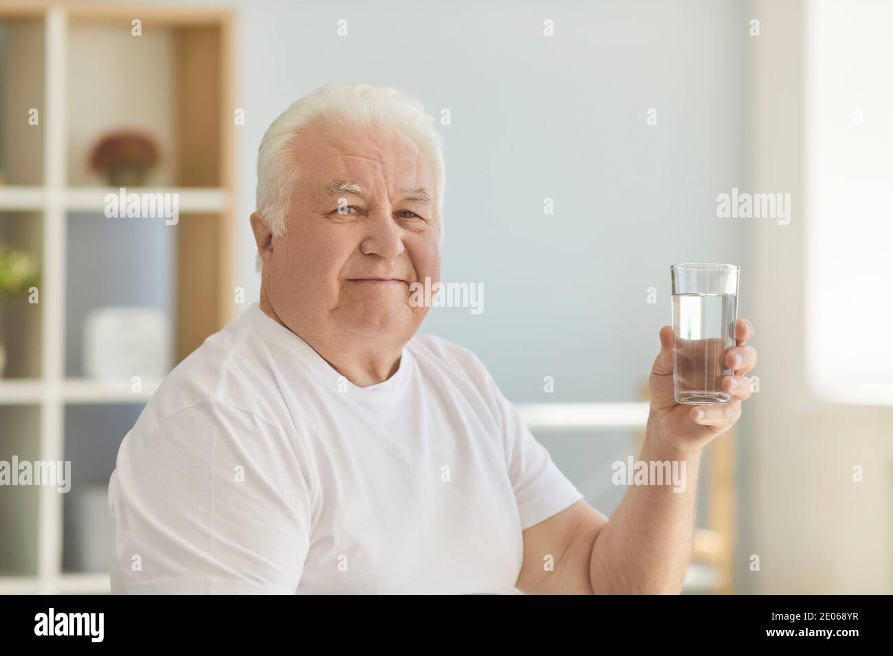 L'uomo anziano positivo continua a essere sano prevenendo la disidratazione bevendo abbastanza acqua Foto Stock