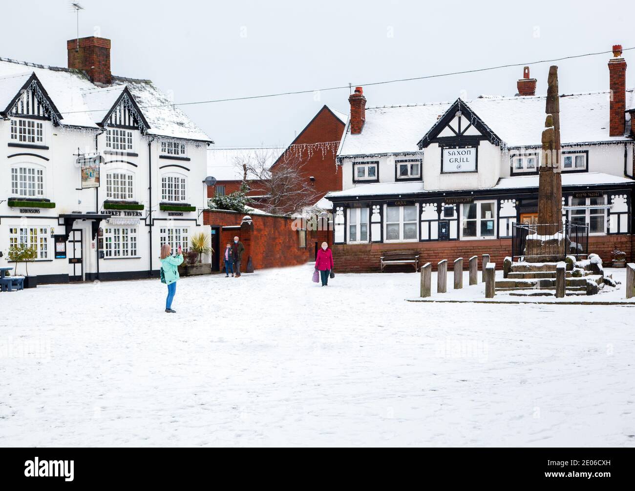 Antiche croci in pietra sassone nel mercato acciottolato innevato Piazza in inverno a Sandbach Cheshire Inghilterra di fronte Di Market Tavern inn Foto Stock