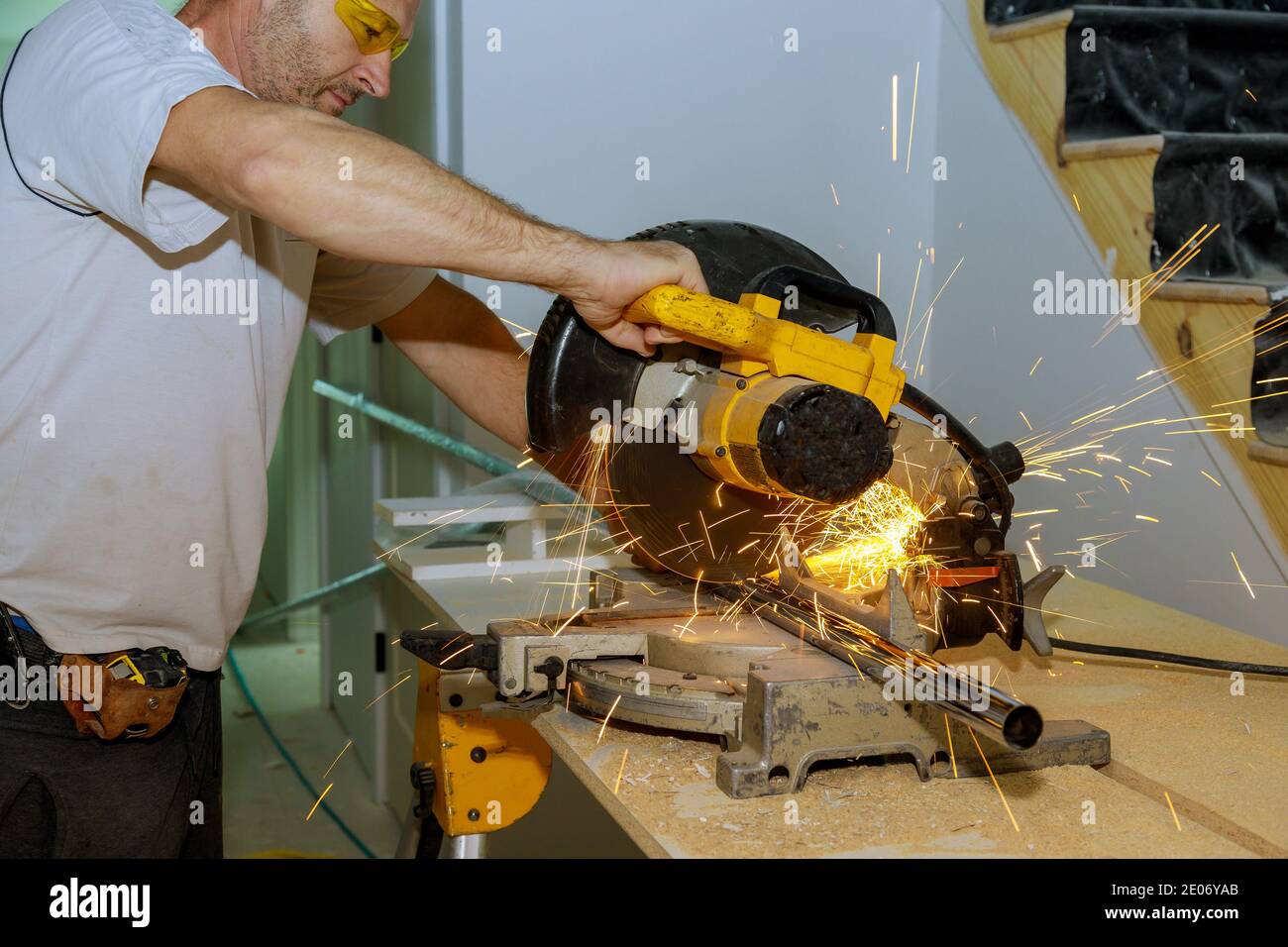 Lavora un uomo che taglia un tubo metallico con una circolare sega con spruzzi di scintille Foto Stock