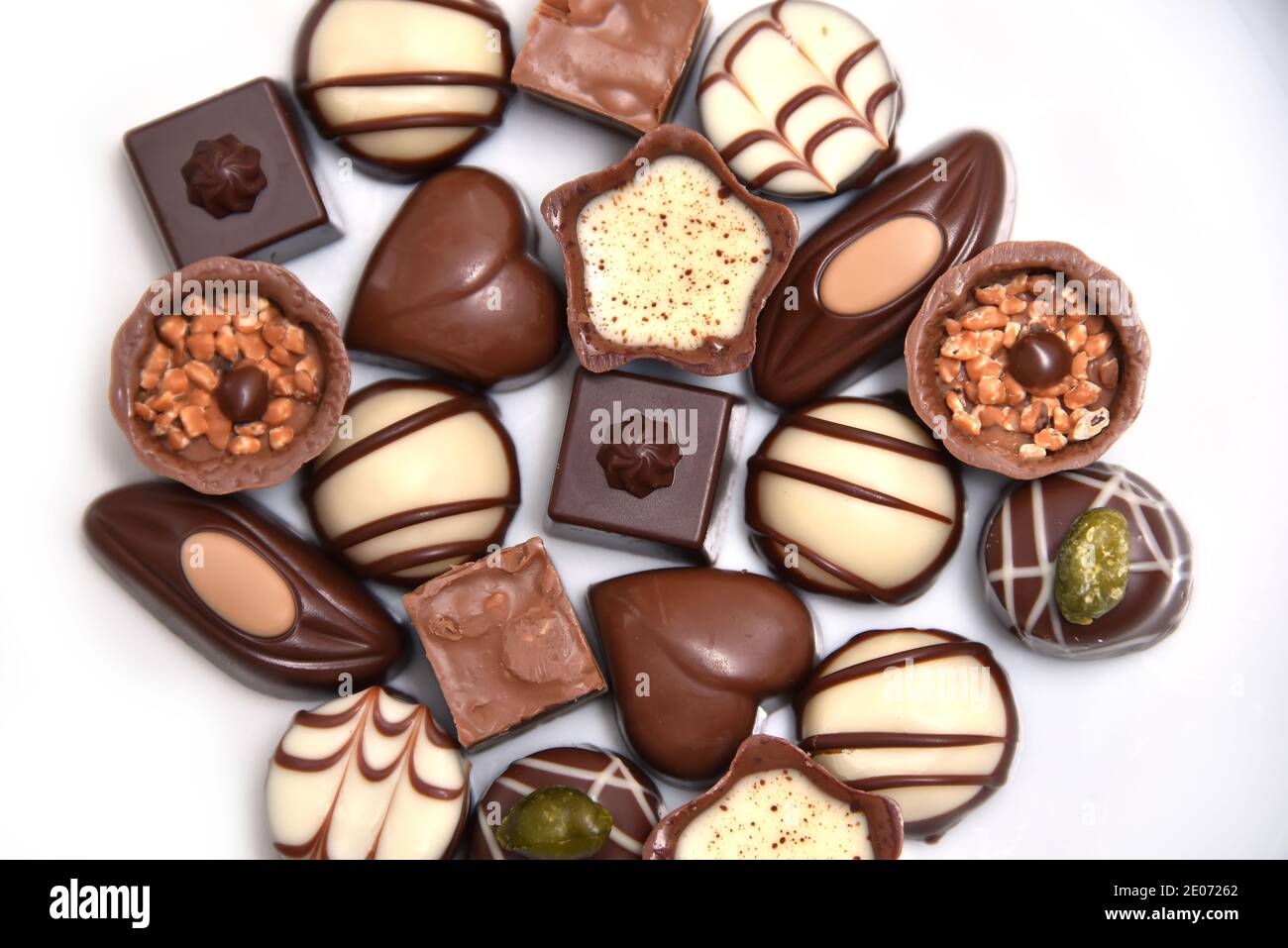 Primo piano con una selezione di cioccolatini di lusso, con una varietà di forme tra cui un cuore, fiorentini e pistacchi. Sono in bianco, latte e dar Foto Stock