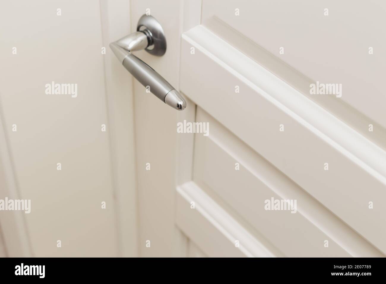 Porta classica in legno bianco fresato con maniglia cromata. Interni scandinavi bianchi Foto Stock