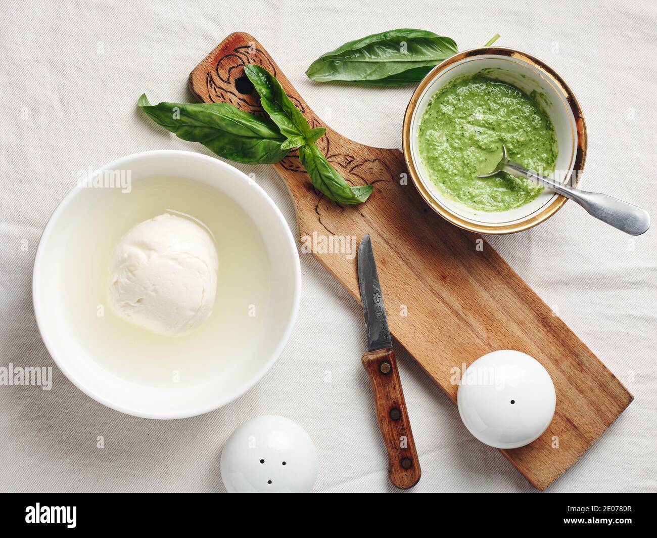 Palla di mozzarella in un recipiente, salsa di pesto e foglie di basilico fresco. Foto Stock