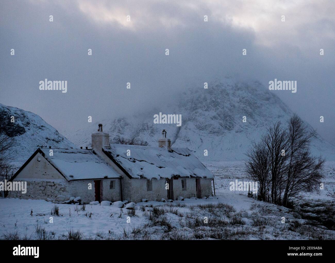 Glencoe, Scozia, Regno Unito. 30 dicembre 2020. Nella foto: Cottage Highland a Glencoe con la famosa montagna triangolare di Buachaille Etive Mòr sullo sfondo con la sua cima avvolta in nube e gelida nebbia. Avvertimento giallo neve in posizione come più neve con temperature di congelamento previsto di nuovo durante la notte. Credit: Colin Fisher/Alamy Live News Foto Stock