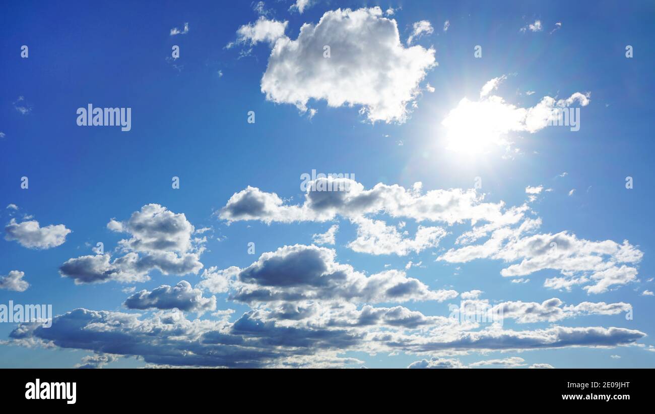 sole luminoso in cielo blu con nuvole bianche Foto Stock