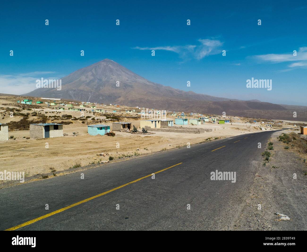 Una strada alla periferia di Arequipa, Perù. Piccole capanne di cemento sono sparse nella zona, mentre il vulcano misti è visto dietro Foto Stock