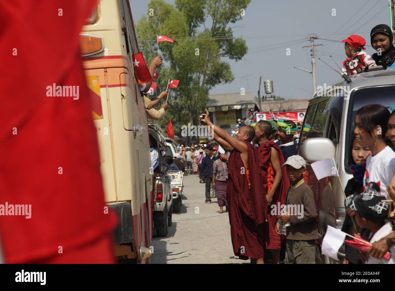 Monaci buddisti scatta una foto dei membri dell'NLD che tessono bandiere rosse dell'NLD. Aung San Suu Kyi, vincitore del Premio Nobel per la pace, in occasione della campagna elettorale del 1° aprile a Kalaw, Myanmar, il 1° marzo 2012. Il leader dell'opposizione del Myanmar si è recato nello Stato Shan come parte della sua campagna elettorale. Indossa un abito tradizionale Shan e una sciarpa per la testa. Foto di Christophe Loviny/ABACAPRESS.COM Foto Stock