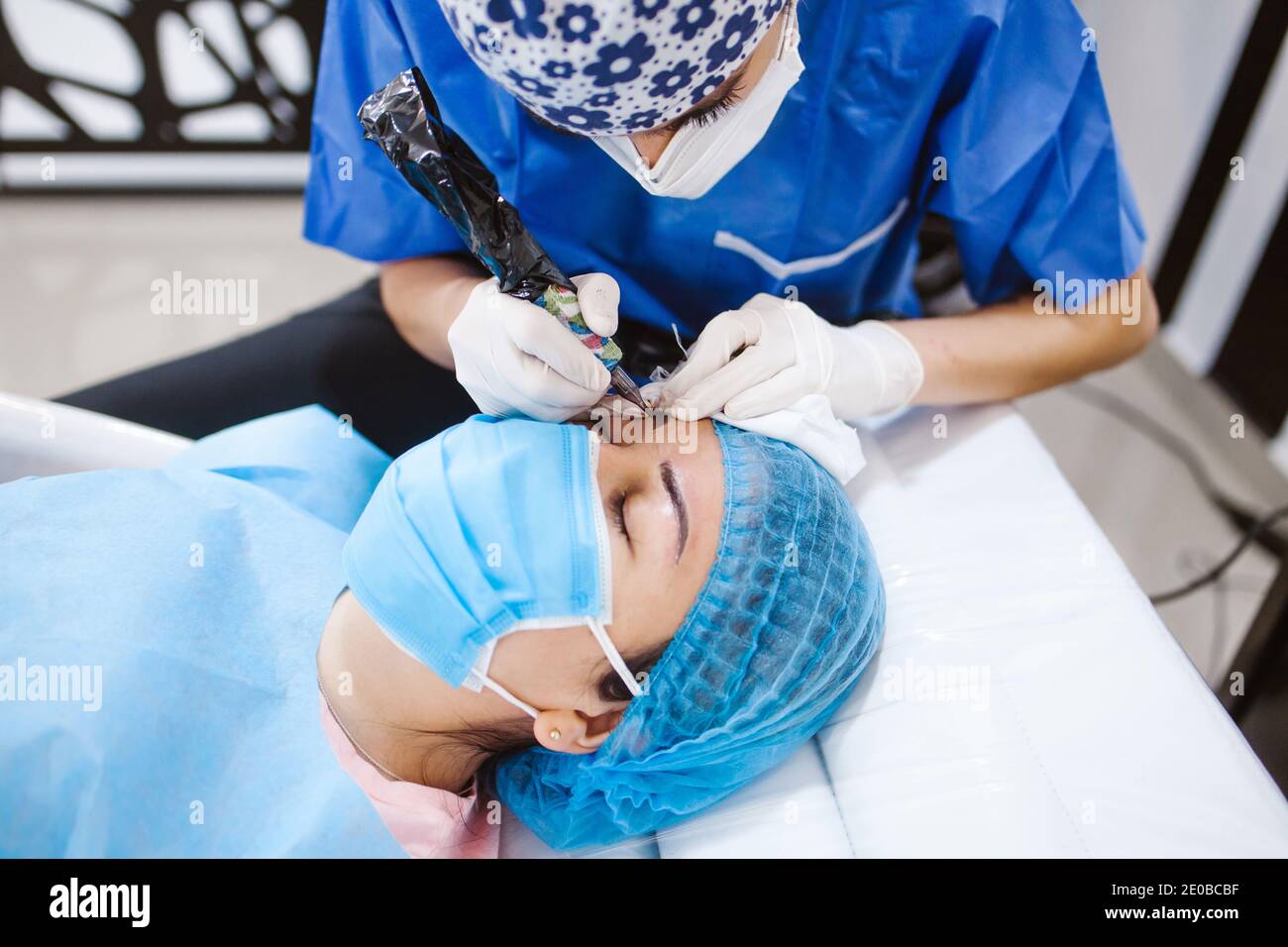 Cosmetologa latina che si prepara alla donna messicana per la procedura di trucco permanente sopracciglia in Messico, closeup Microblading Foto Stock