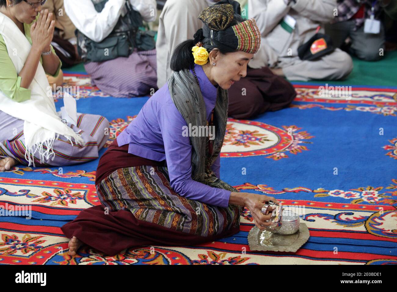 Aung San Suu Kyi, vincitore del Premio Nobel per la pace e presidente della Lega nazionale per la democrazia (NLD), indossa un costume tradizionale shan, versa un tè ai monaci in un monastero durante una riunione di campagna a Lashio, nello Stato dello Shan settentrionale, Myanmar, il 18 marzo 2012. Questo è un simbolo da condividere con tutti i meriti che si ottengono dopo aver fatto una donazione al monastero. Suu Kyi ha raggiunto gli elettori di etnia cinese e minoritaria prima delle elezioni presidenziali del 1° aprile. Foto di Christophe Loviny/ABACAPRESS.COM Foto Stock