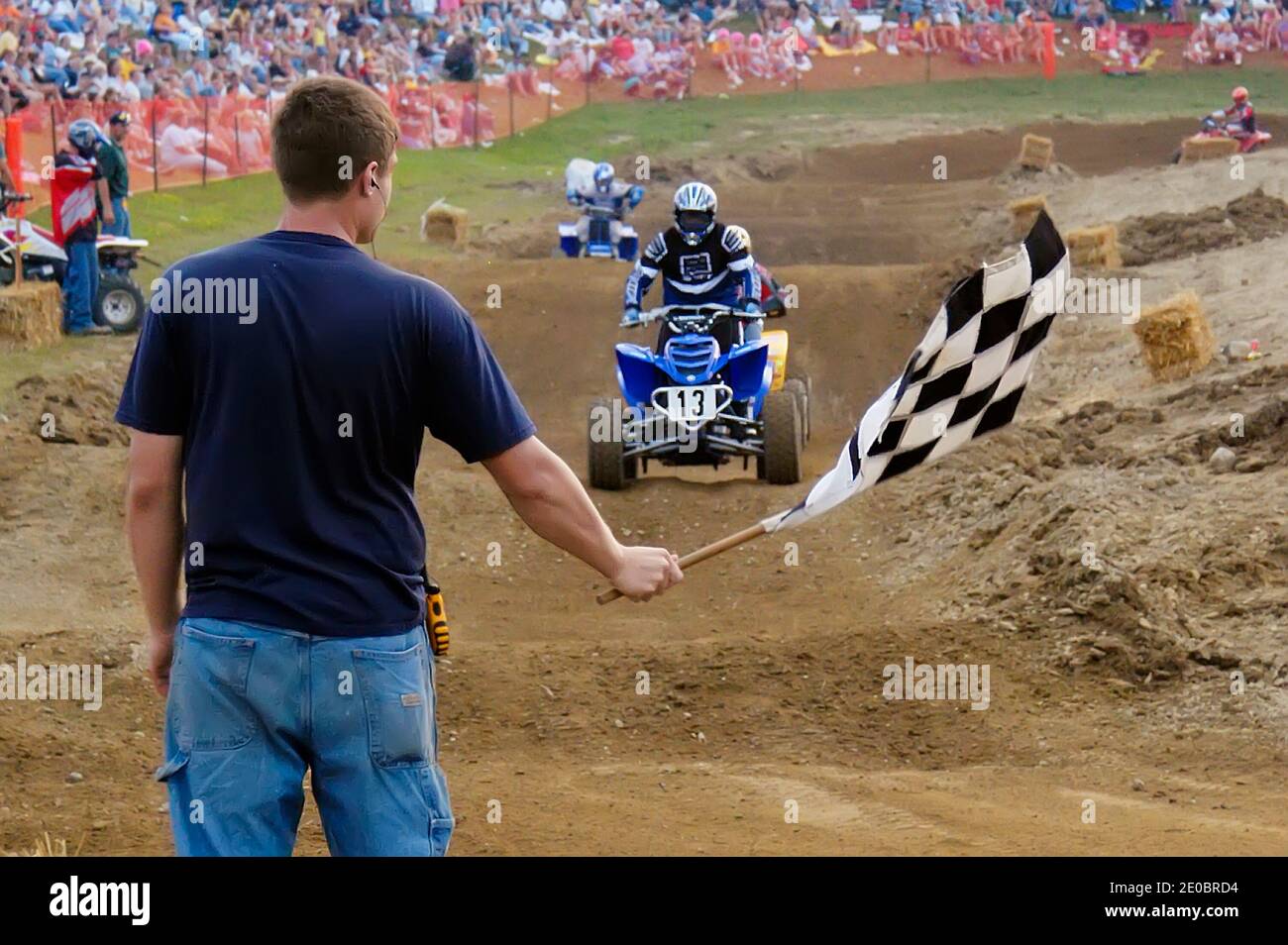 Contestent prende la bandiera a scacchi mentre attraversa il traguardo Linea in una gara fuoristrada ATV Foto Stock