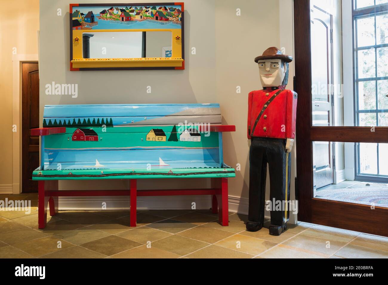 Canadian Mountie e panca d'arte popolare dipinta in blu, verde e rosso accanto all'ingresso all'interno della casa contemporanea Foto Stock