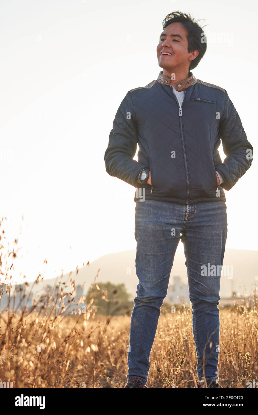 Uomo in jeans blu, giacca blu, T-shirt bianca, con occhiali, in profilo  guardando l'alba in un campo d'oro e il sole sullo sfondo peeking o Foto  stock - Alamy