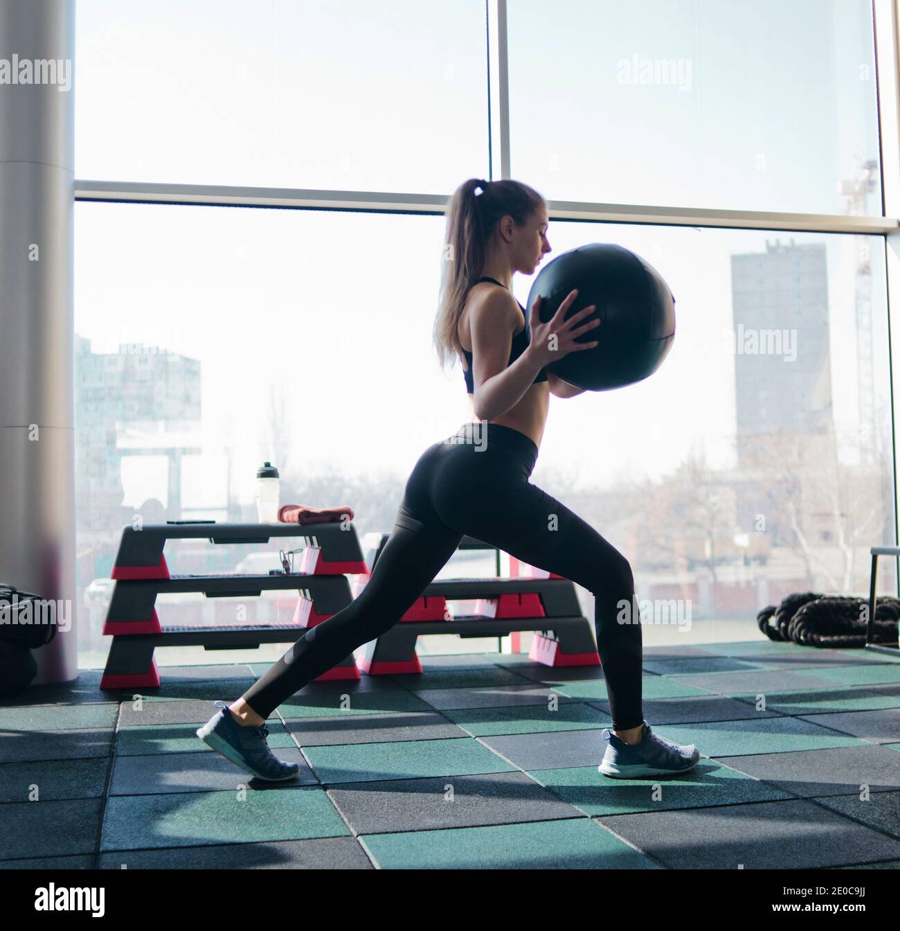 Fitness giovane donna allenamento con palla medica in mano sullo sfondo di  una grande finestra panoramica in palestra. Formazione funzionale Foto  stock - Alamy