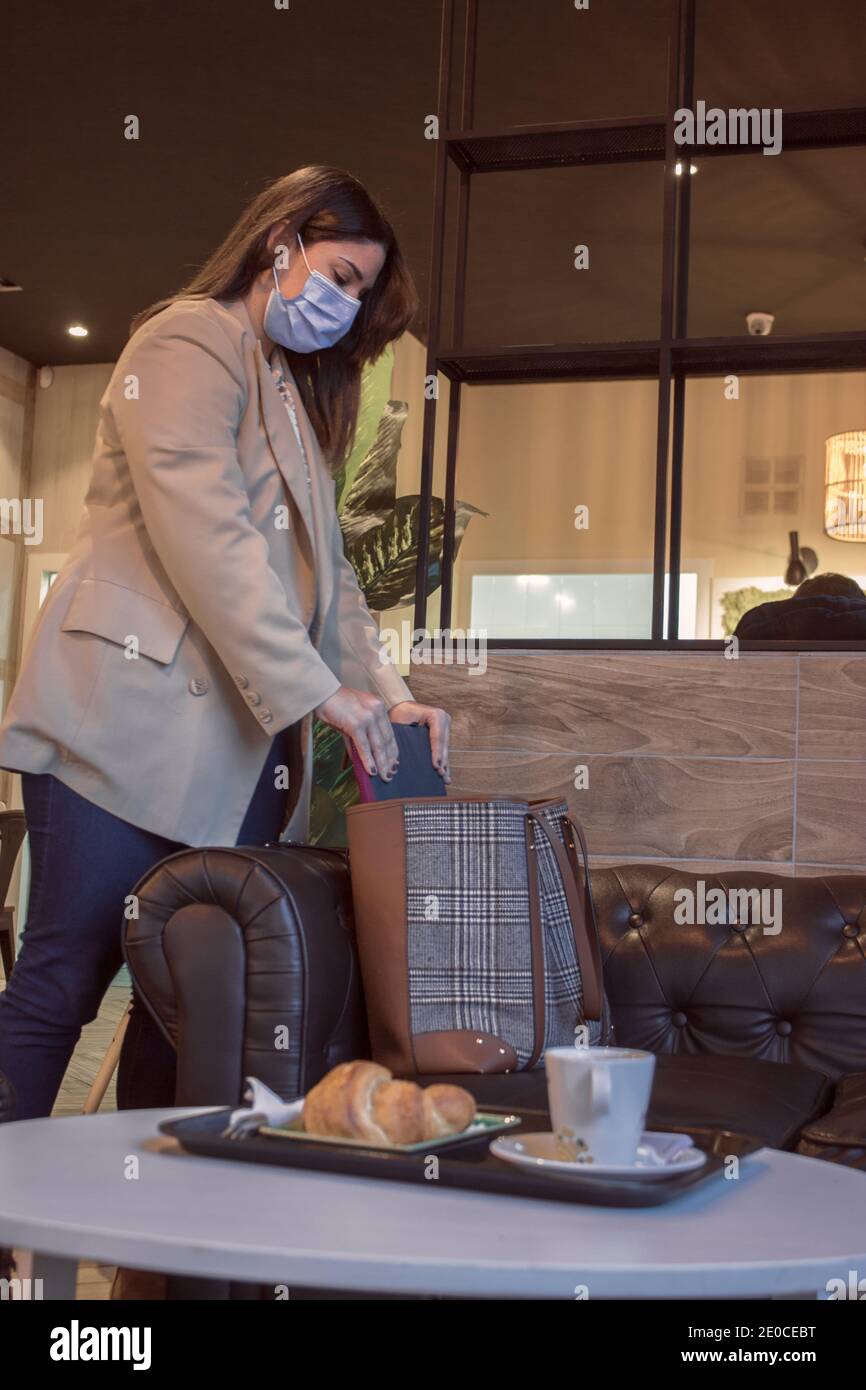 La giovane ragazza prende il suo laptop dalla borsa in una giornata di lavoro mentre fa colazione in una caffetteria. Concetto di Boss ragazza 2021. Foto Stock