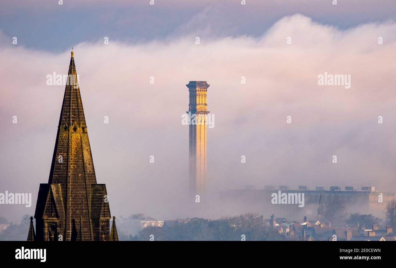 Bradford, West Yorkshire, Regno Unito. 31 dicembre 2020. Misty si affaccia sulla valle di Bradford mentre il Regno Unito continua con un incantesimo freddo. Il potente camino industriale dell'ex Listers Mill può essere visto, catturando il sole mentre si alza dalla nebbia. Credit: Mick Flicynn/Alamy Live News Foto Stock