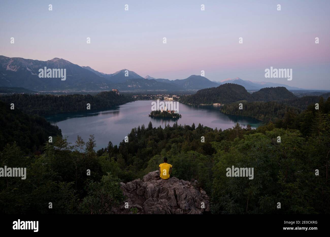 Giovane uomo che gode di vista panoramica tramonto sul Lago Bled Island Blejsko jezero da Osojnica punto panoramico collina superiore carniolan Julian alpi Montagne in Slov Foto Stock