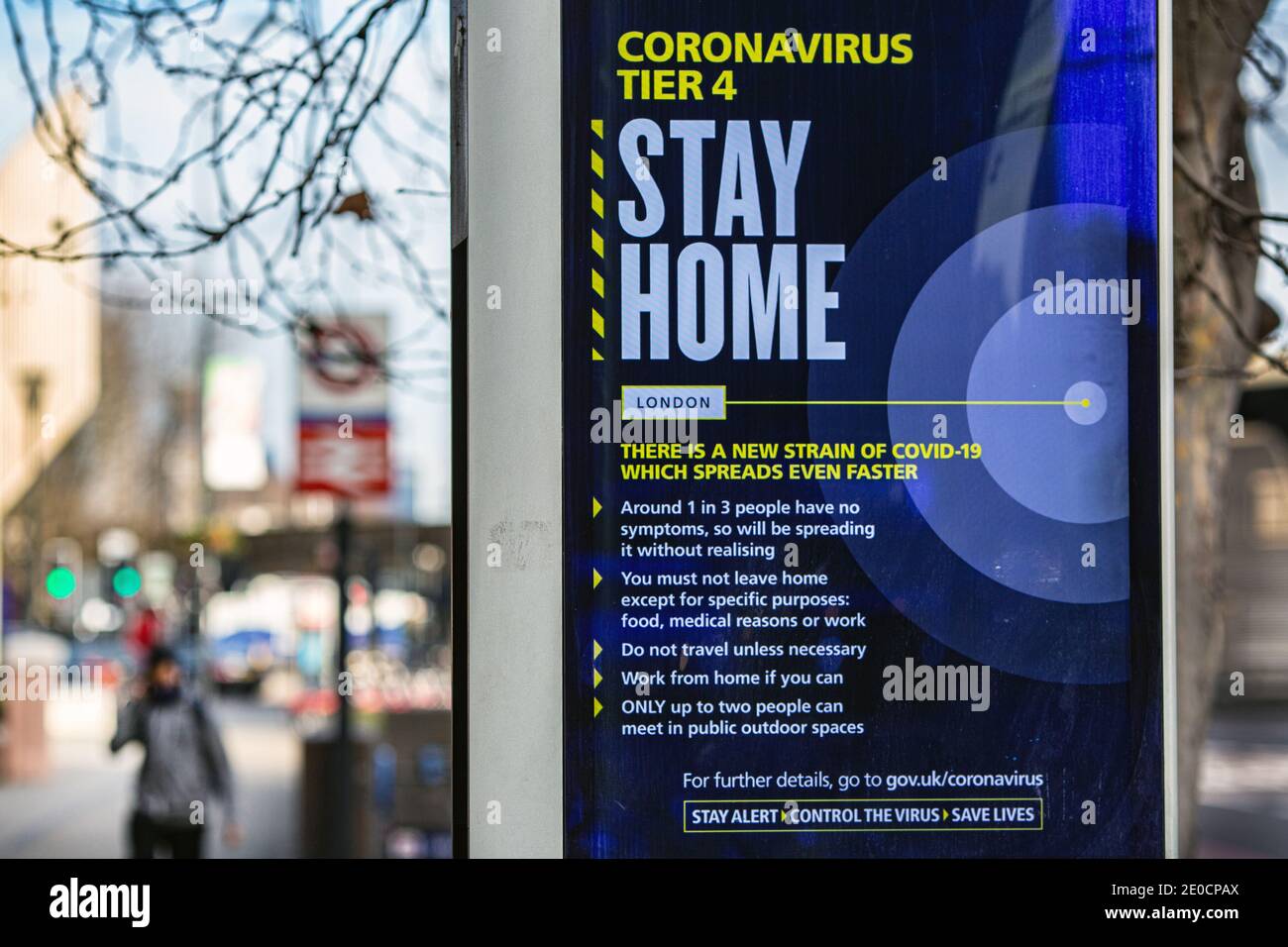 Un uomo cammina oltre un'insegna di incoronavirus 'Stay Home' a Vauxhall. Londra è stata messa sotto le restrizioni di livello 4 come picchi di casi e nuovi ceppi di COVID- Foto Stock