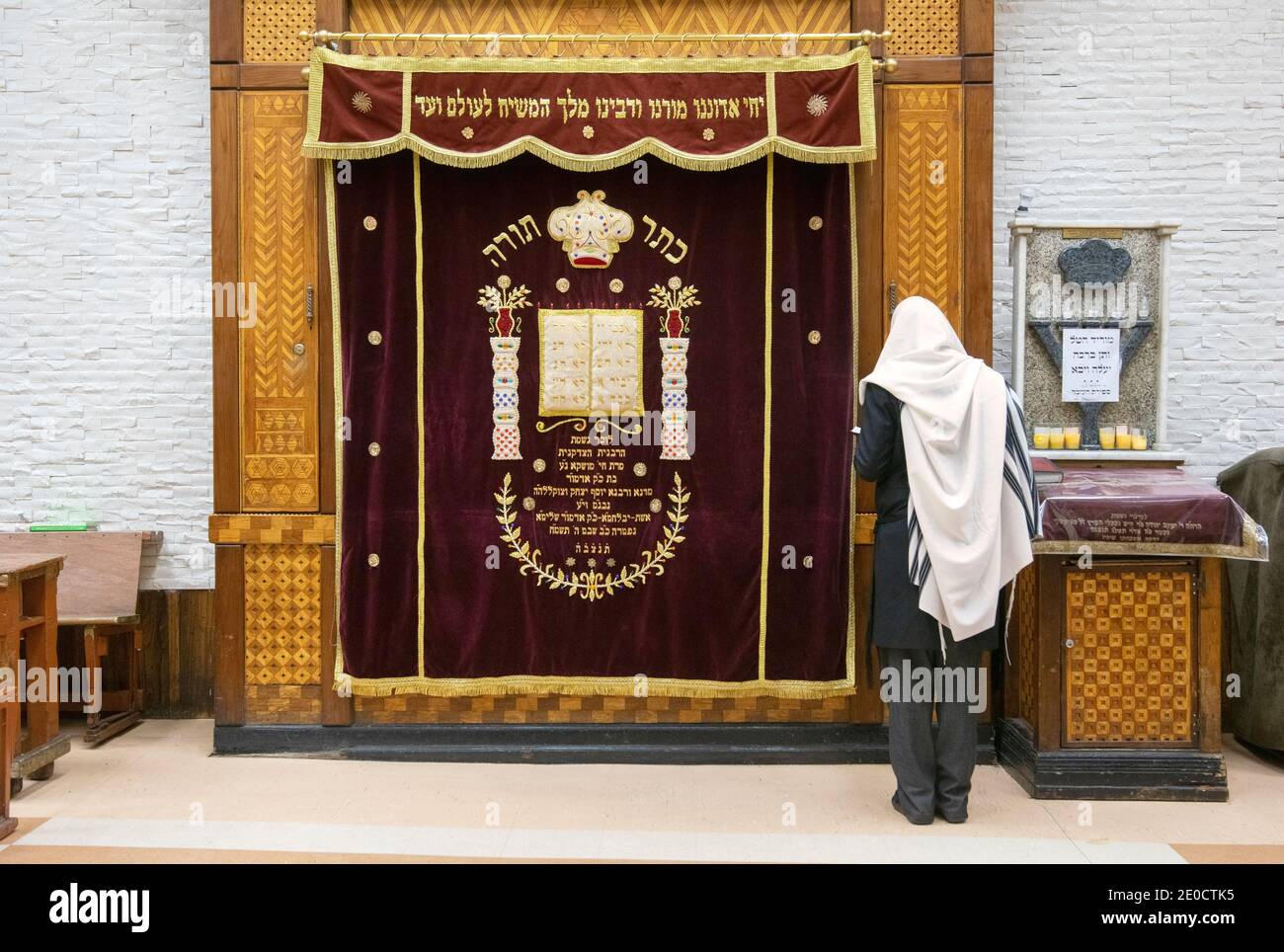 Un uomo ebreo non identificato in uno scialle di preghiera prega di fronte all'Arca Santa ornata presso la sinagoga principale di Lubavitch a Crown Heights, Brooklyn, New York. Foto Stock