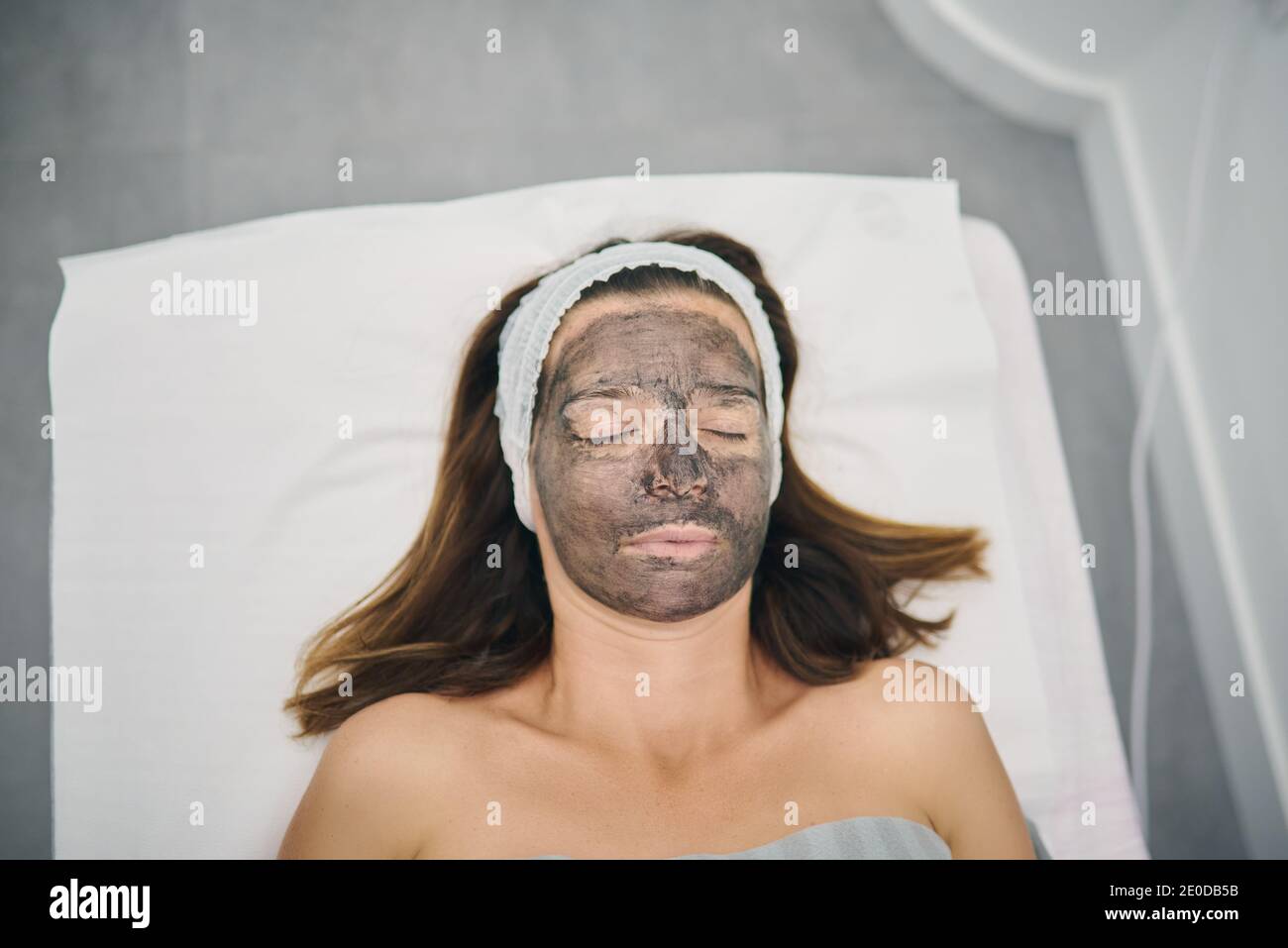 Da sopra cliente femminile con lozione di carbonio sulla preparazione del viso per la pelatura laser in un moderno centro di bellezza con gli occhi chiusi Foto Stock