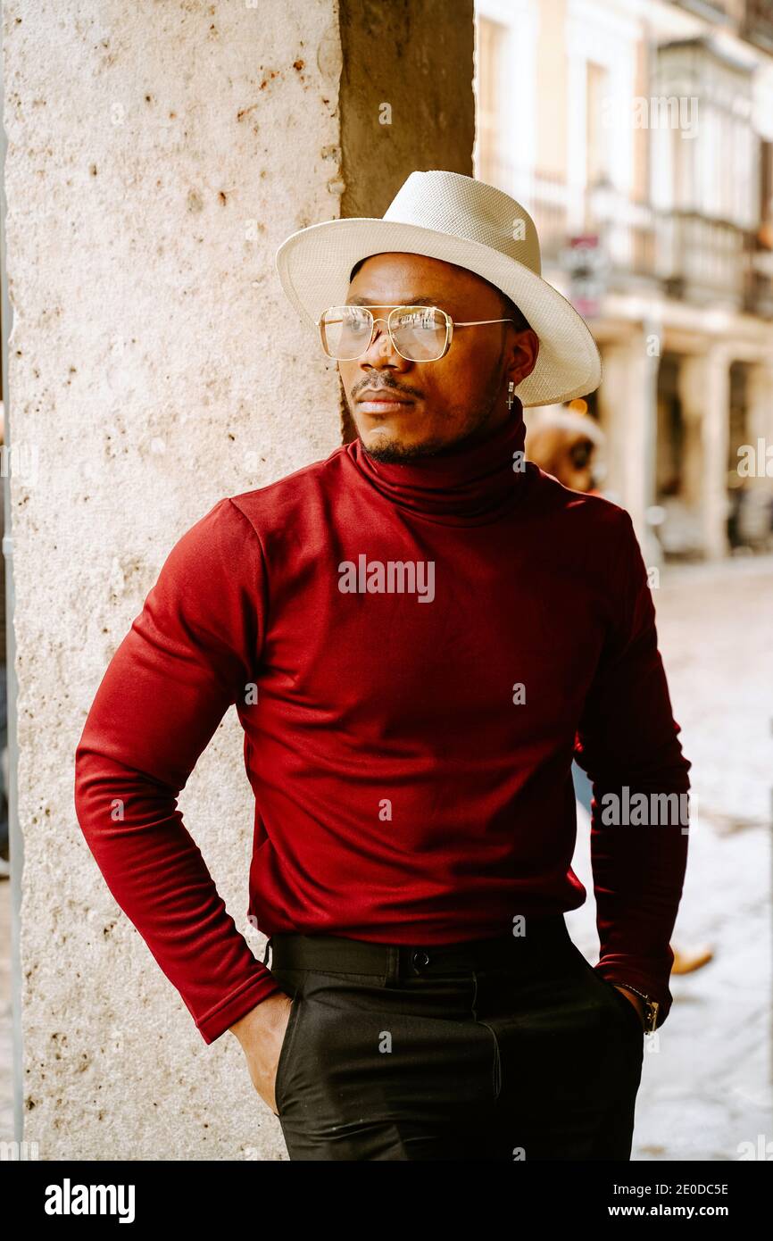 Determinato afroamericano maschio indossando cappello elegante e vestiti in  piedi in strada che guarda via Foto stock - Alamy