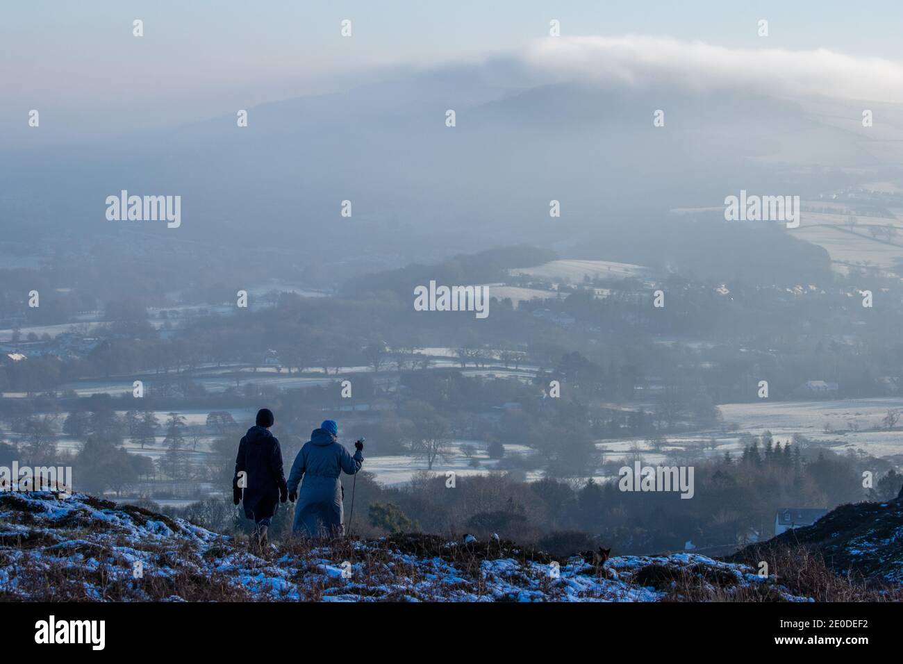 Tempo nel Regno Unito - 31 dicembre 2020: Il sole della neve e la nebbia leggera aggiungono un tocco di festa a Burley Moor a Wharfedale la vigilia di Capodanno. Due persone camminano un cane lungo il bordo di Burley Moor in incredibili condizioni di entry. West Yorkshire Rebecca Cole/Alamy News (c) Foto Stock