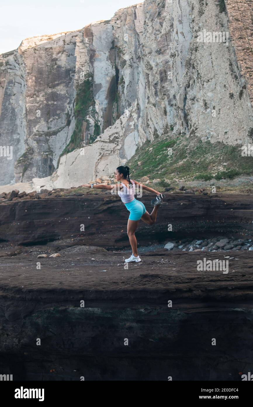 Vista laterale di FIT femmina in piedi in Natarajasana e bilanciamento sulla gamba mentre si fa yoga in montagna Foto Stock